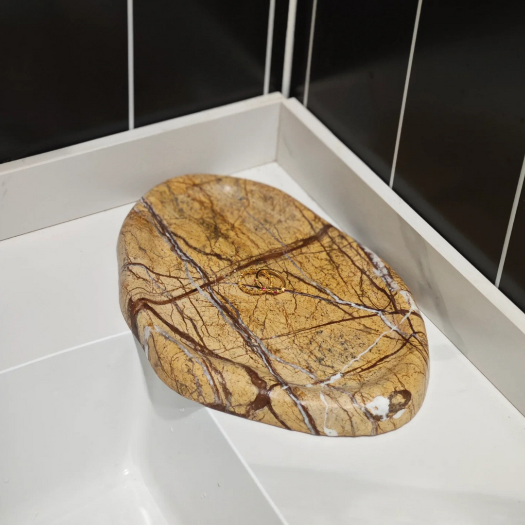 Natural marble tray with earthy patterns placed on a white sink, perfect for elegant bathroom decor.