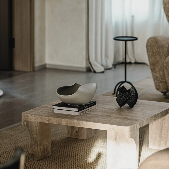 Neutral-toned living room featuring a ceramic bowl centerpiece on a travertine table with modern furnishings.