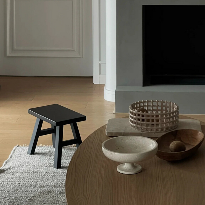 Neutral travertine bowl on a wooden table in a minimalist decor setup.