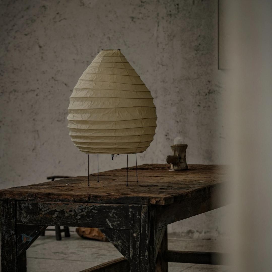 Rounded paper floor lamp casting ambient glow in an earthy-toned Japandi interior.
