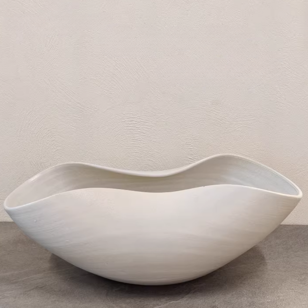 Organic ceramic bowl styled in a warm minimalist living room featuring curved furniture and natural materials.