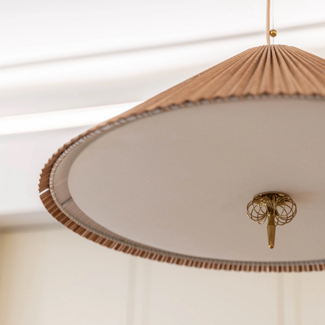Minimalist bamboo pendant above round stone table in an organic modern interior