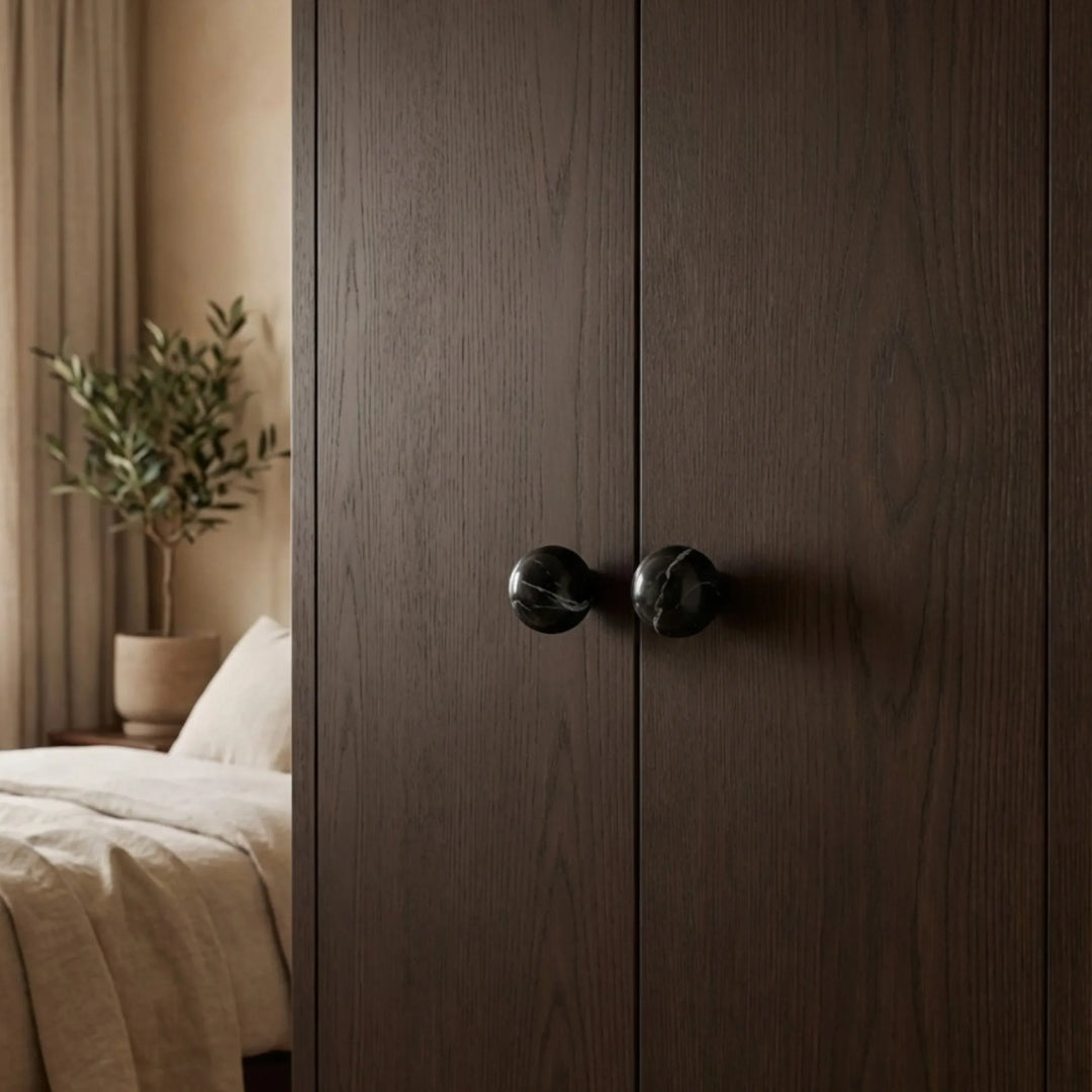 Organic modern bedroom with dark wardrobe fronts detailed in black stone knobs for a quiet focal point.