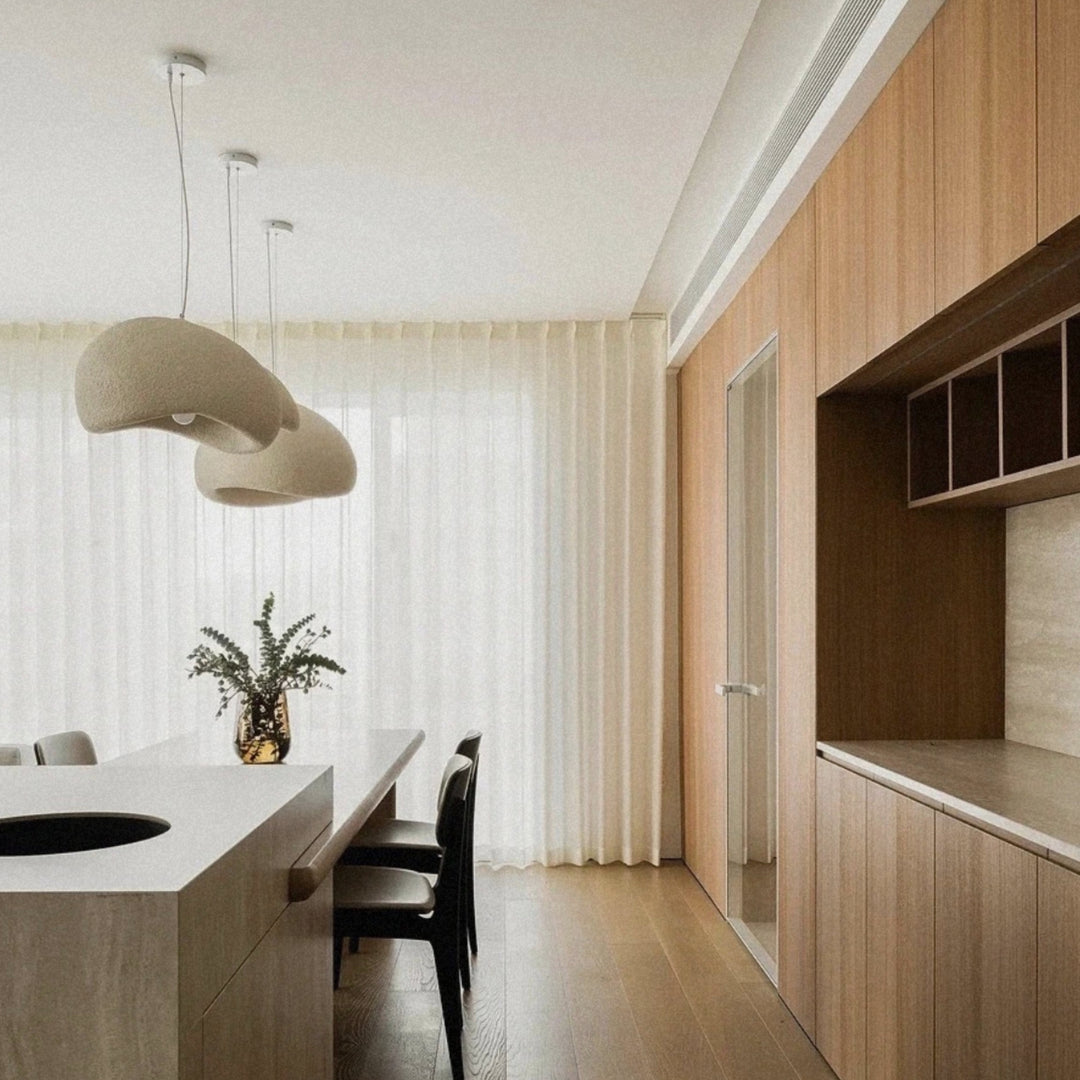 organic shaped pendant light suspended above a kitchen counter near dining chairs.