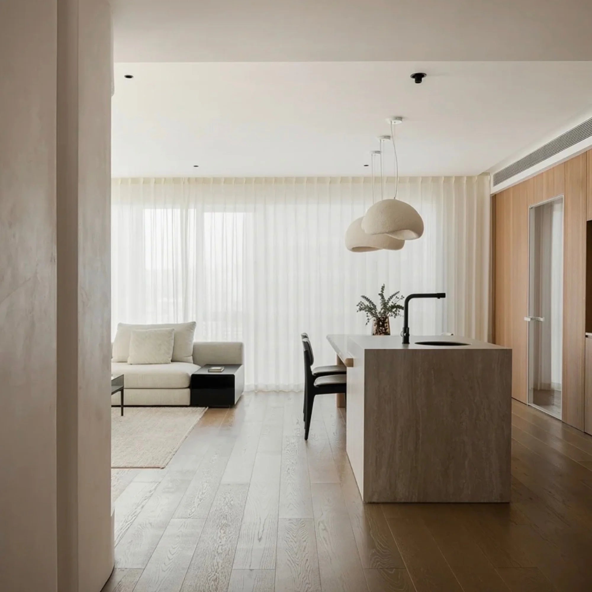 Oxi ceiling light above kitchen island in a soft modern open-plan living space.