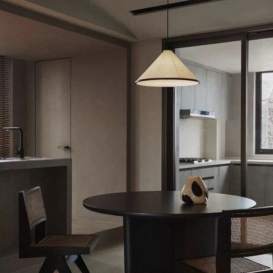 paper pendant light hanging above a round dining table in a minimal interior.