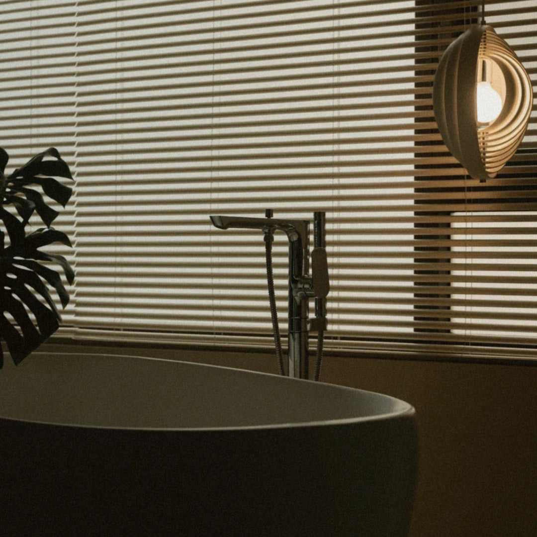 pendant light placed near a bathtub and window blinds creating soft ambient light.