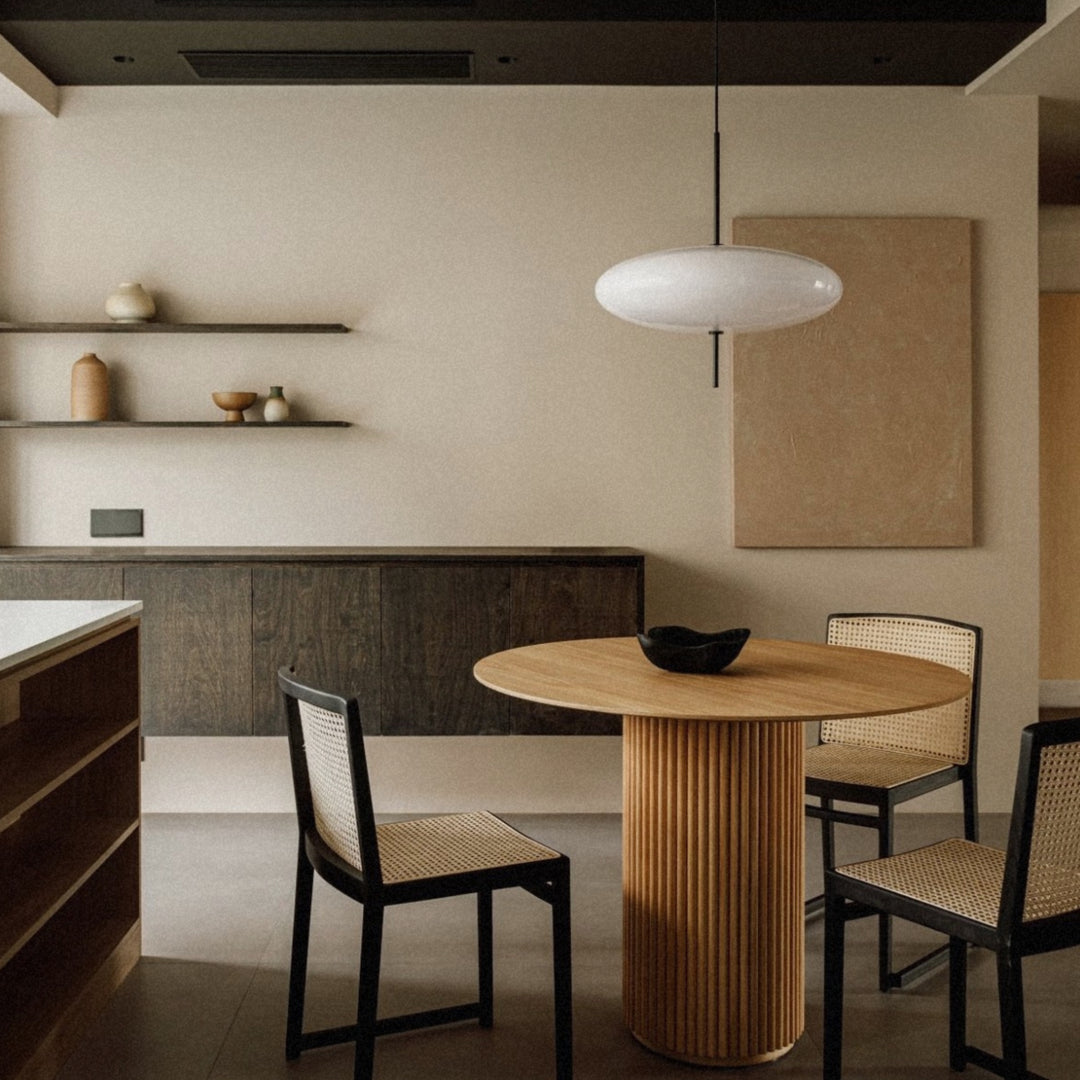 pendant light suspended above a dining table in a clean modern interior.