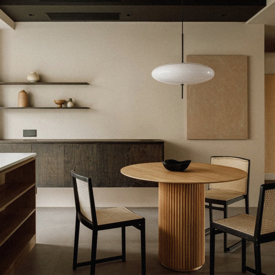 pendant light suspended above a dining table in a clean modern interior.