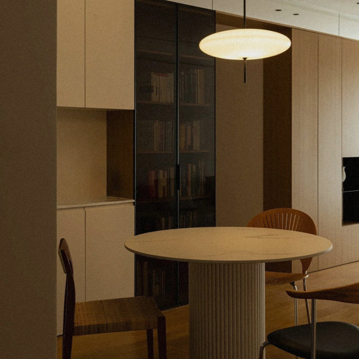 pendant light used over a round table in a kitchen dining area.