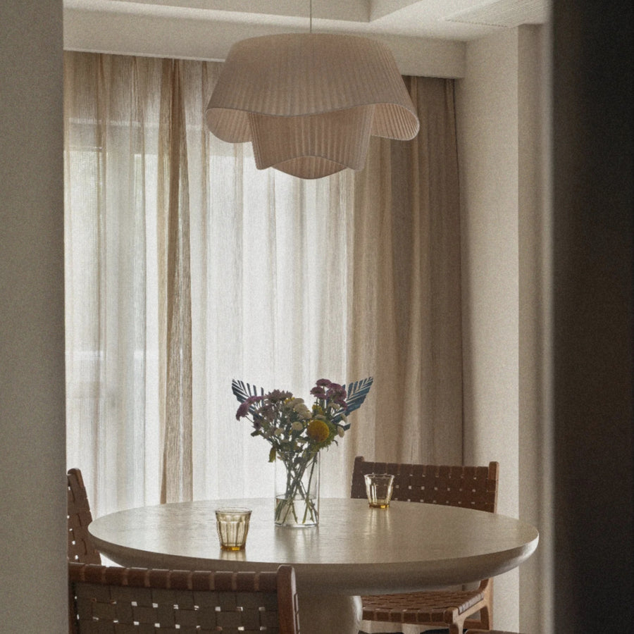 pleated fabric pendant light hanging above a dining table in a soft neutral dining room interior.