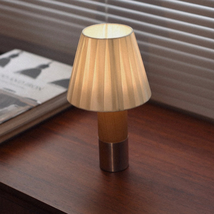 pleated shade table lamp standing on a wooden surface with soft warm glow.