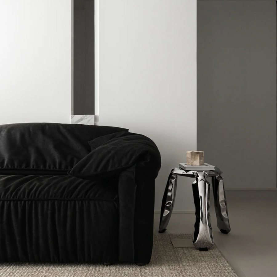 Polished metal stool accentuating a contemporary living room's modern aesthetic.