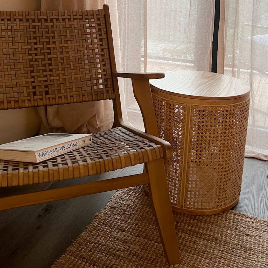 Rattan side table placed in a cozy living room setting next to a wooden chair