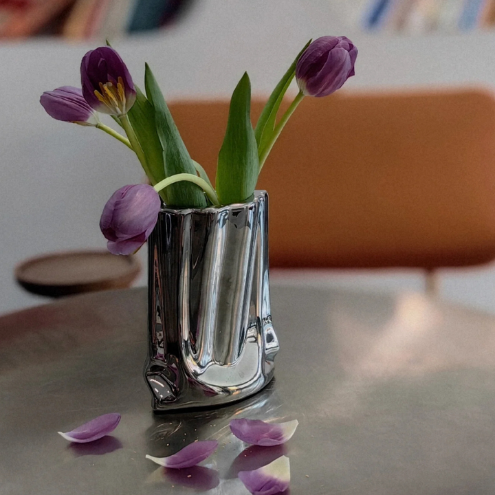 Reflective modern vase with purple tulips, adding sleek elegance to a contemporary table setting.