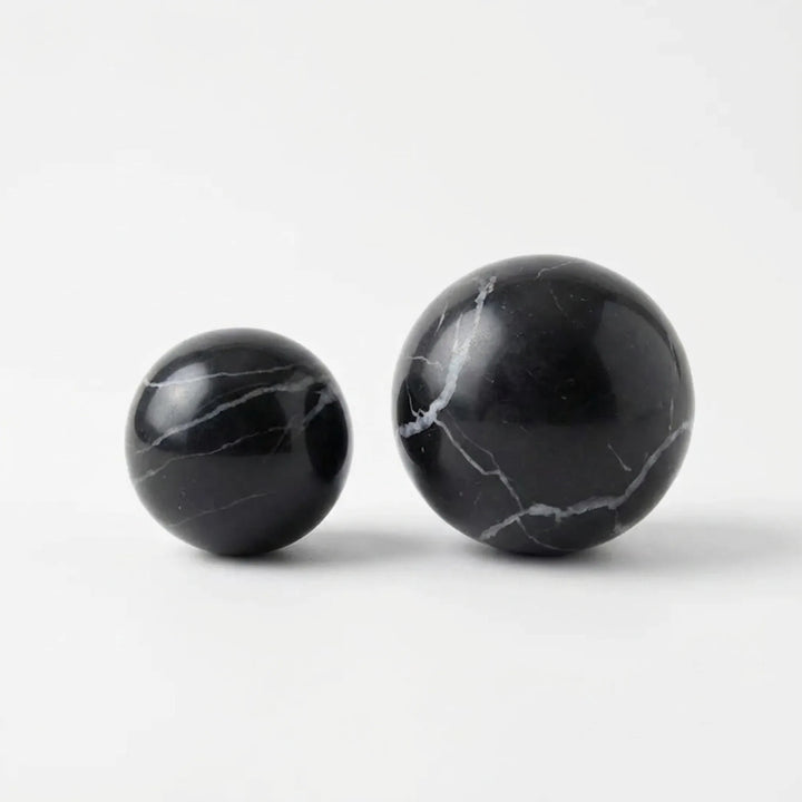 Studio shot of round black marble cabinet knobs on a white background, ready for cupboards or wardrobes.