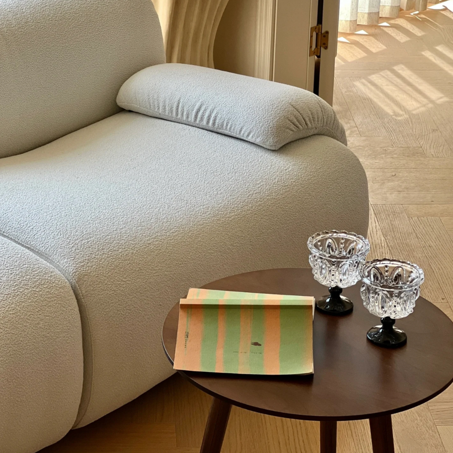 Scandinavian minimalist living room with modern glassware on wooden side table and soft textured sofa