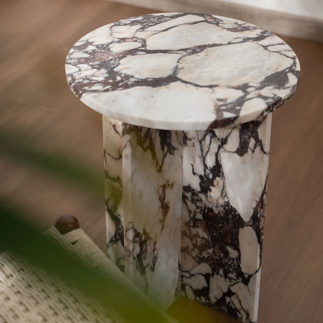 Sculptural marble coffee table with bold veining and grounded form, styled for soft modern interiors