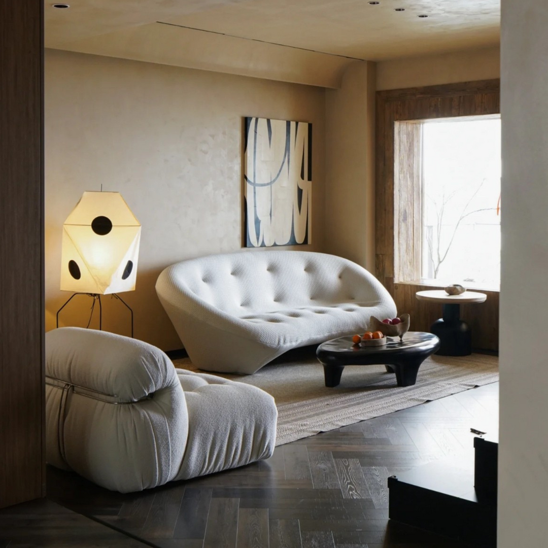 Placed next to a white sofa, this sculptural floor lamp enhances the modern, neutral-toned living room decor.