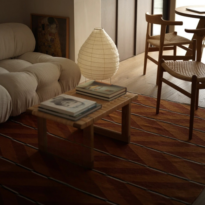 Sculptural floor lamp placed near a low wood table in an organic modern living space with neutral textures.