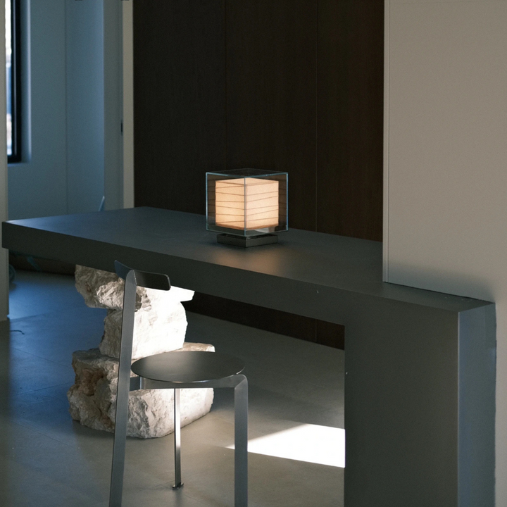 Sculptural table lamp placed on modern console with stone base and neutral palette