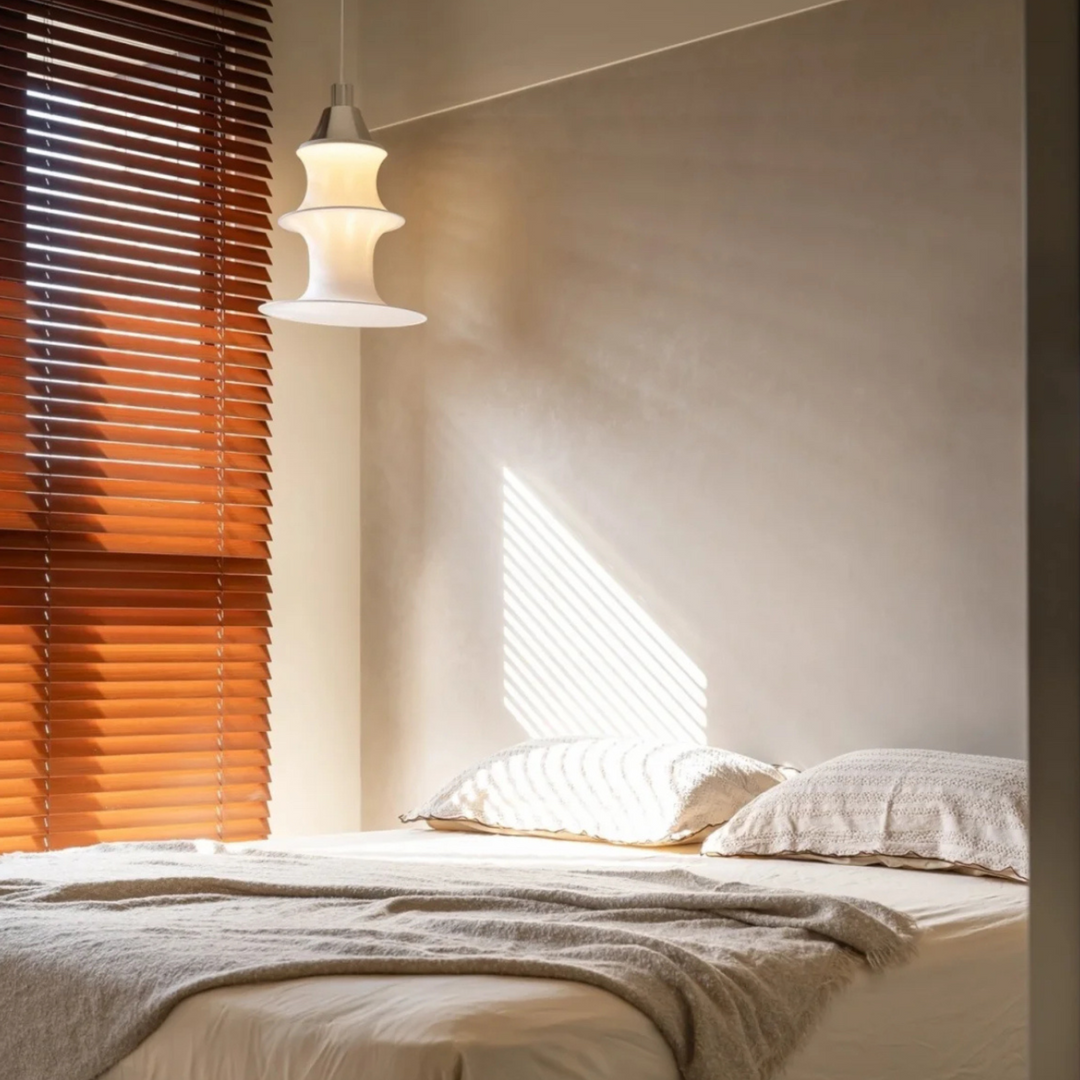White sculptural pendant light turned on in minimalist bedroom