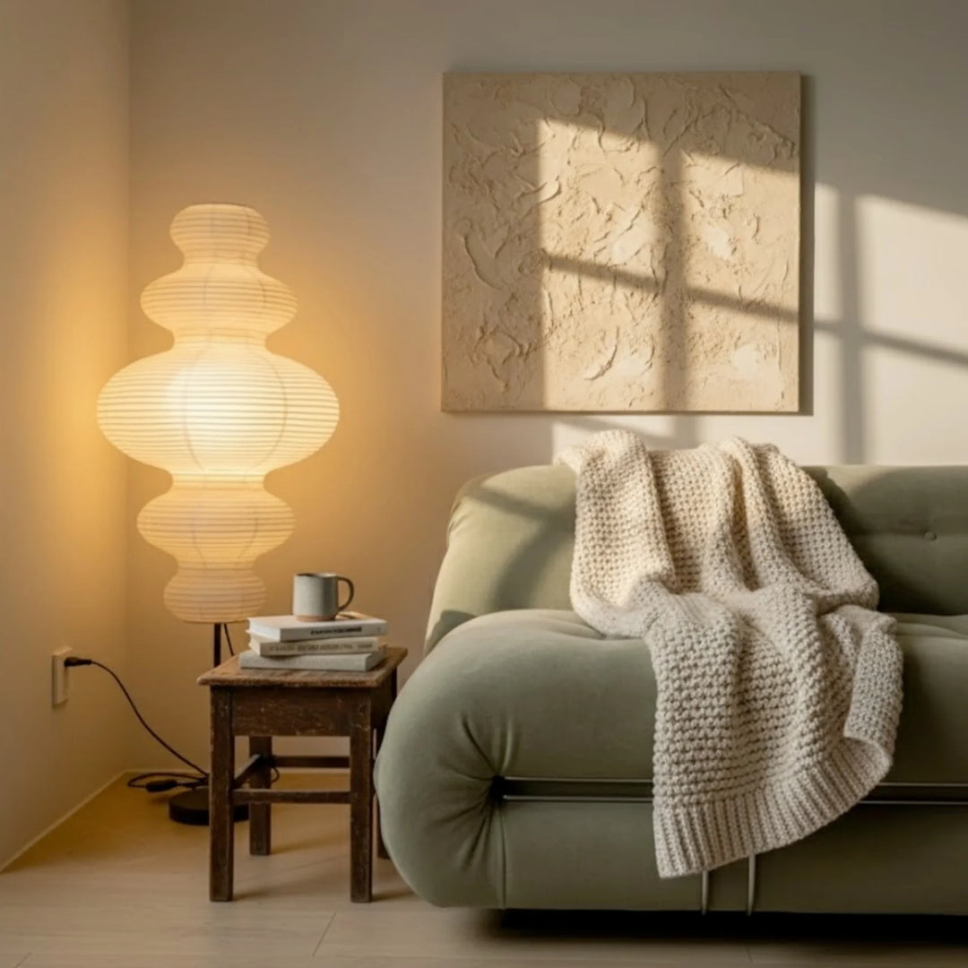 Sinsu paper floor lamp beside a sofa and wooden side table with a calm, handmade feel.