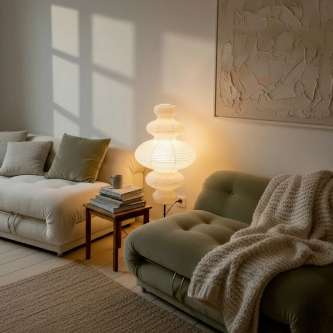 Tall Sinsu floor lamp placed between a white sofa and olive green lounge chair with soft daylight.