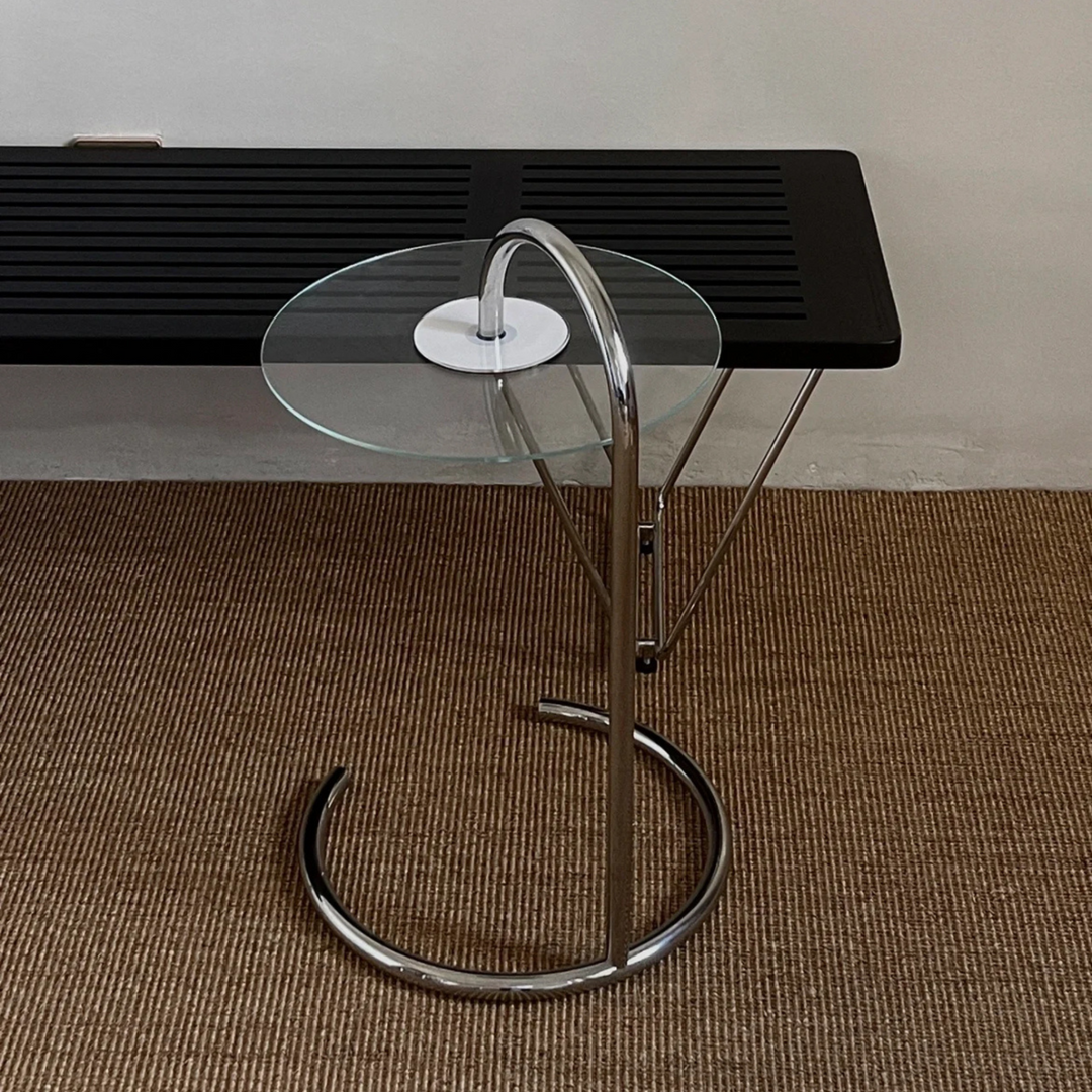     Sleek glass side table in a stylish living room setting, ideal for modern home decor, featuring a minimalist aesthetic and chrome detailing.