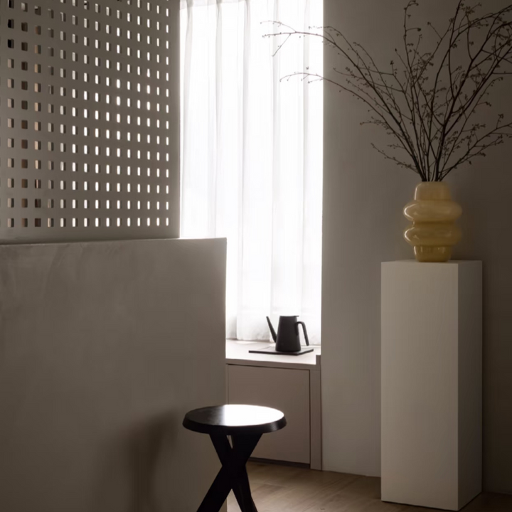 Contemporary home office corner featuring a modern chair and tall vase beside a window.