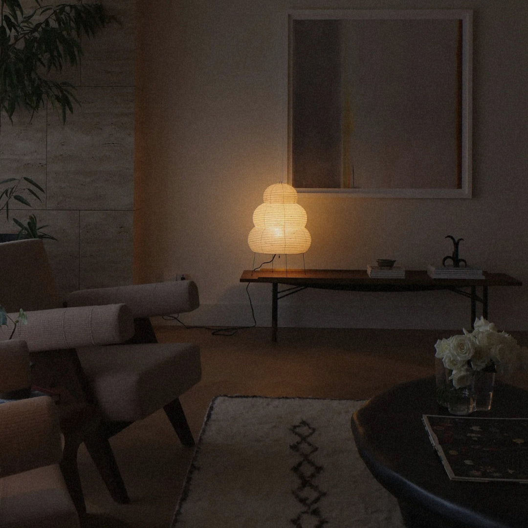 soft paper floor lamp lighting a lounge area beside seating and a low table.