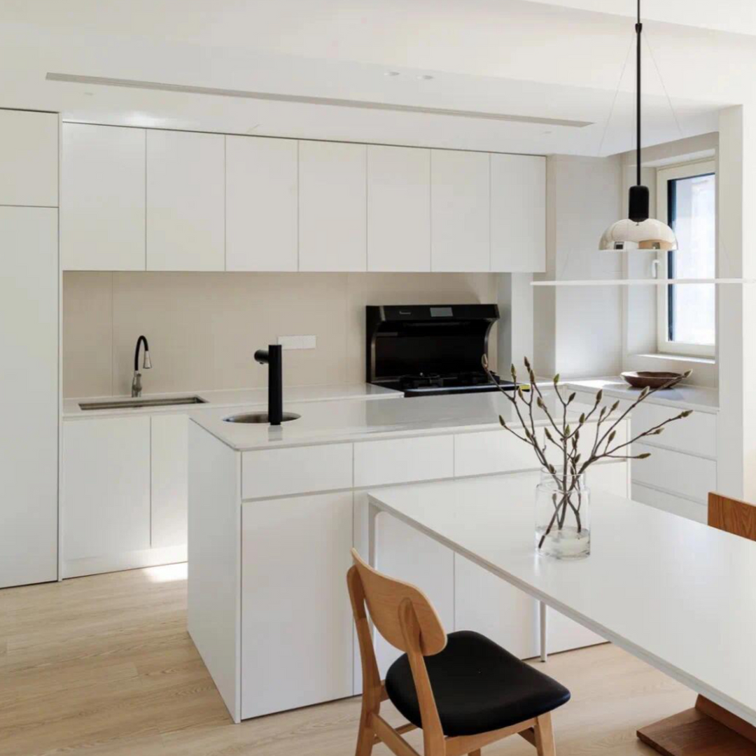 Spacious modern kitchen with chrome pendant light, light wood cabinetry, and white dining table