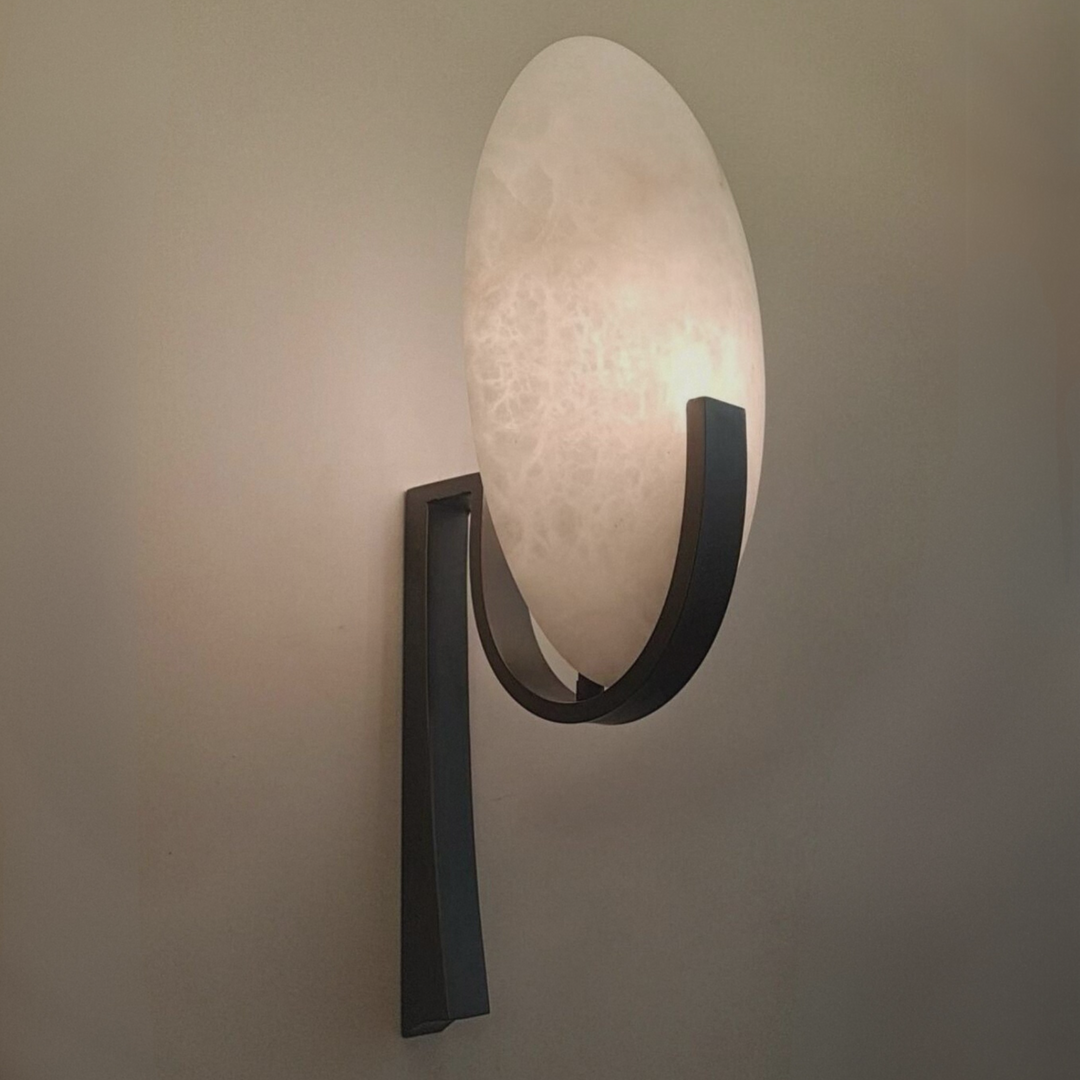 Close-up of a Spanish marble wall lamp with smooth veining, emitting a warm, glare-free glow.