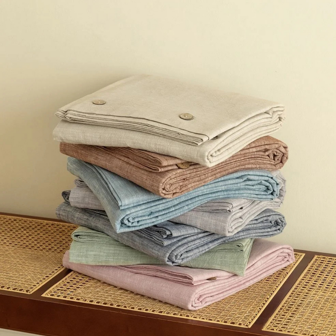 Stack of multicolored linen bed sheets, featuring a variety of pastel tones