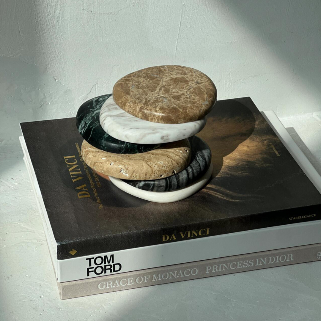 tack of assorted marble coasters on luxury art books featuring Da Vinci and Tom Ford, blending sophistication with modern home styling.