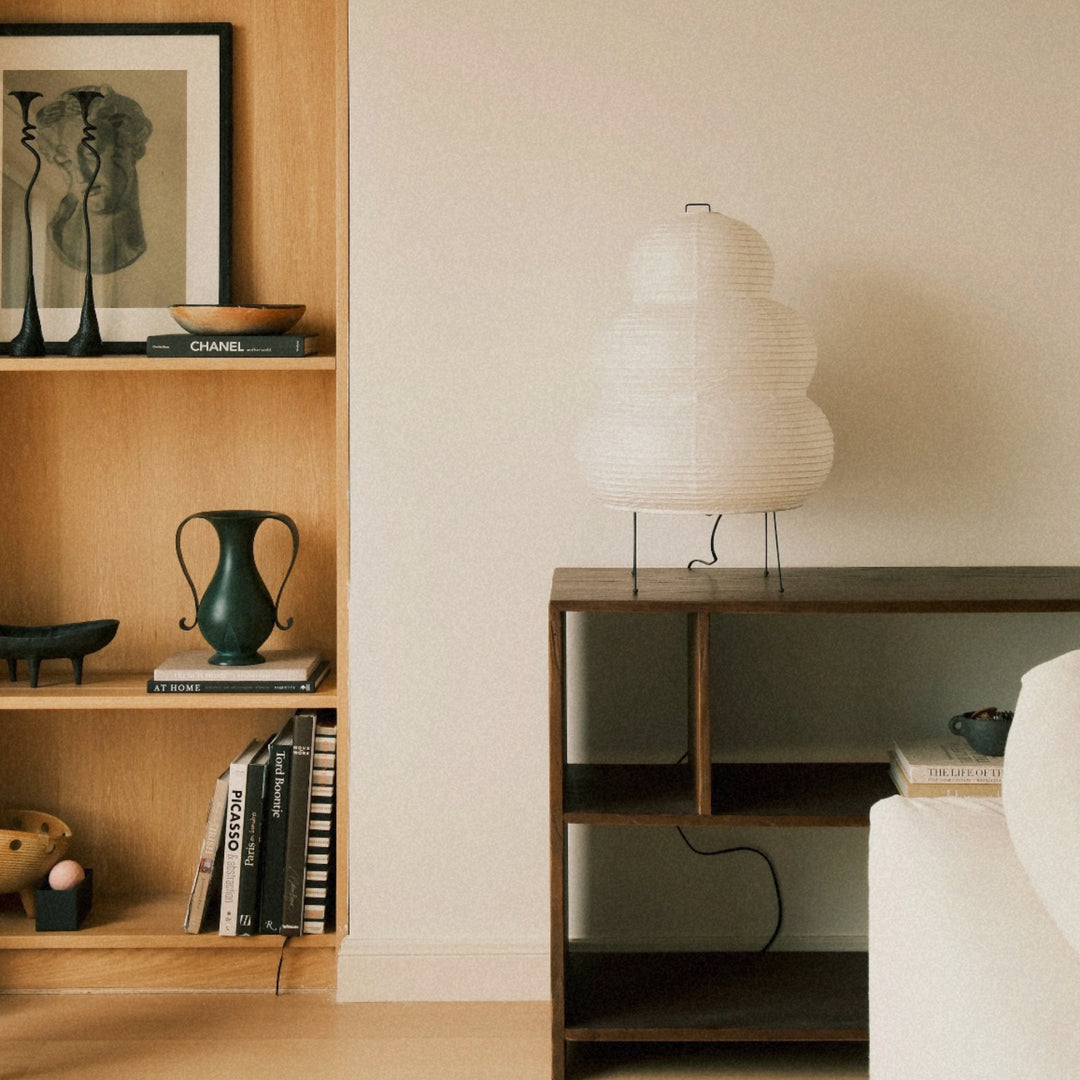 stacked paper floor lamp displayed near a shelf within a warm contemporary room.