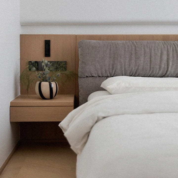 next to the bed a striped glass vase adds a graphic decorative detail to the bedside table.