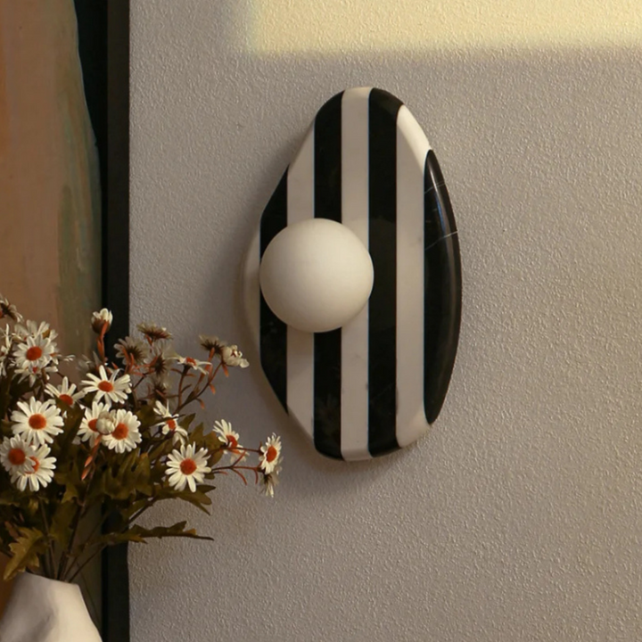 Side view of striped black and white marble wall lamp with a minimalist design.