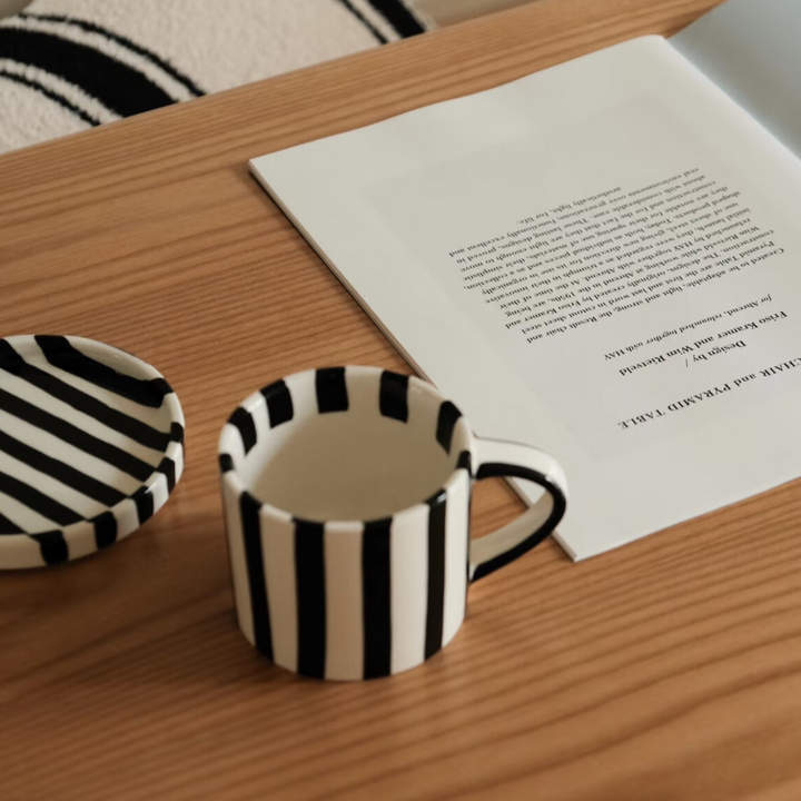 Hand-painted striped mug on a minimalist wooden coffee table, perfect for modern homes.