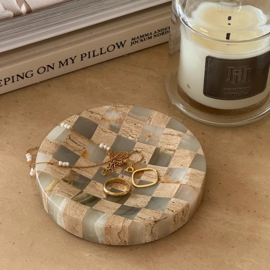 Stylish checkerboard tray crafted from jade marble and travertine, accessorized with rings on a light table.