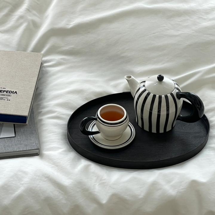 Morning tea set with teapot and mug on a bedside tray, ideal for a relaxing start to the day.