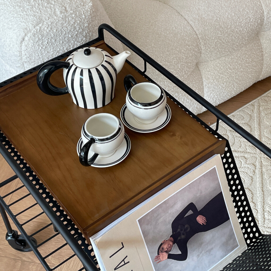 Chic teapot and mug set on a wooden coffee table in a cozy living room, enhancing home comfort and style.