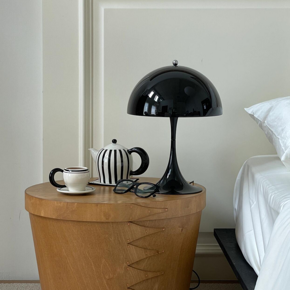 Elegant teapot and mug on a modern desk setup with a contemporary lamp and glasses, perfect for a stylish morning routine.