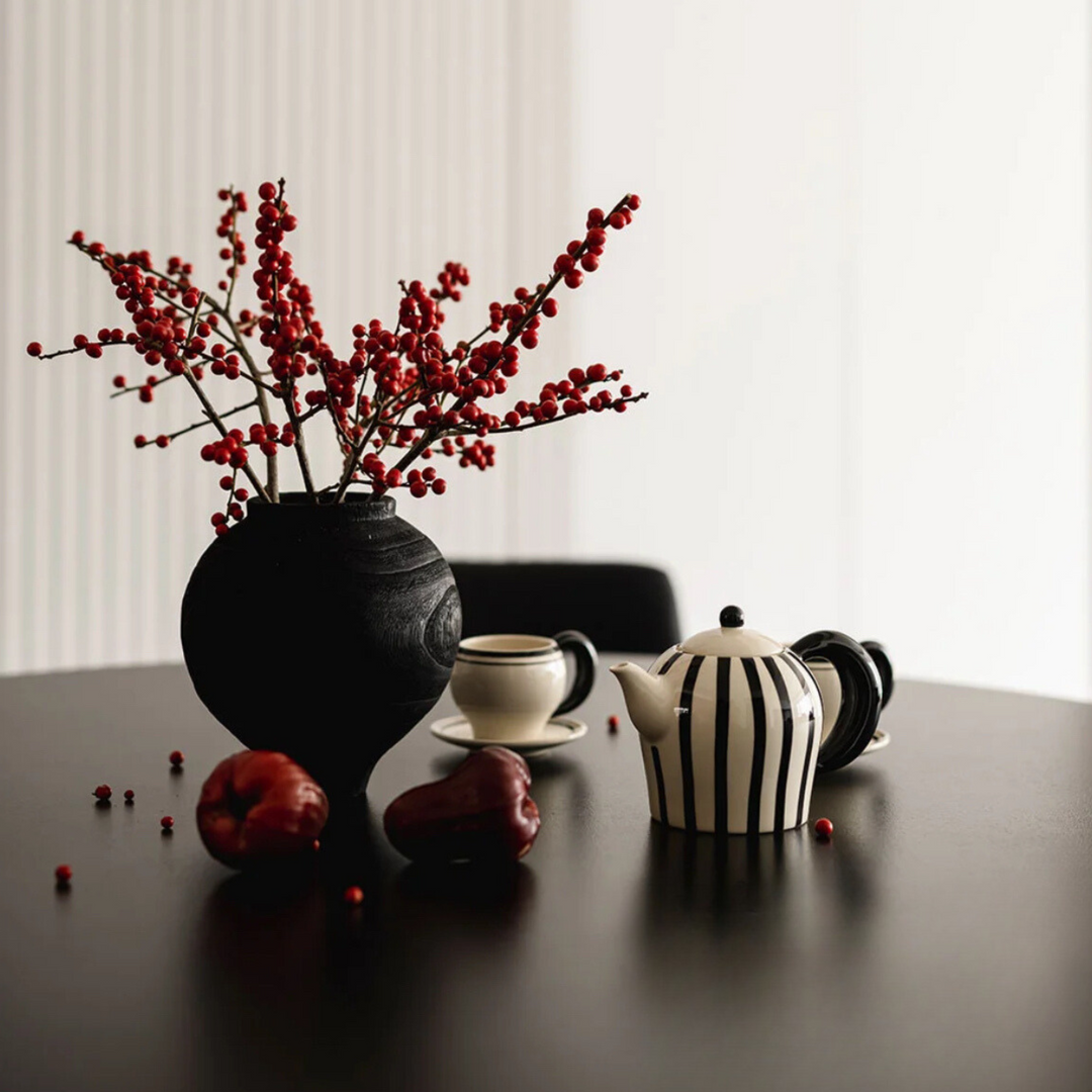 Teapot set with decorative vase and modern decor, styled on a dark dining table.