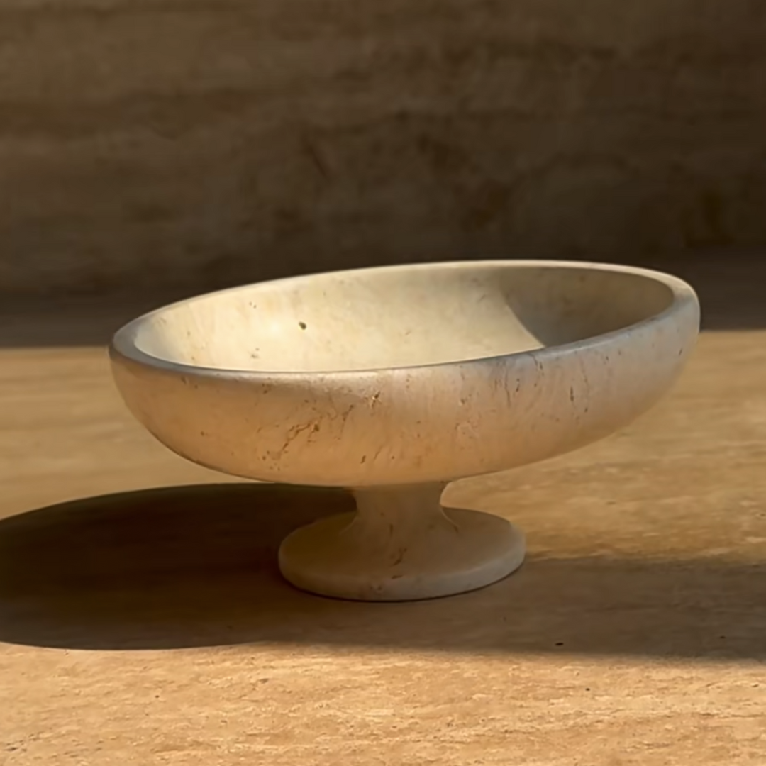 Handcrafted travertine bowl with a textured beige finish in natural light.