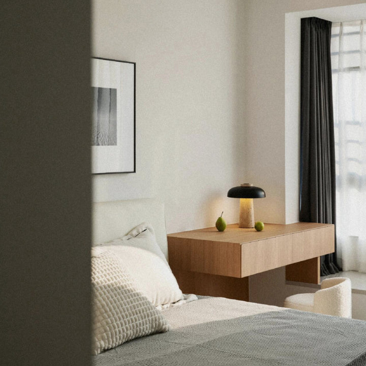 travertine and iron table lamp positioned beside a bed within a quiet modern bedroom.