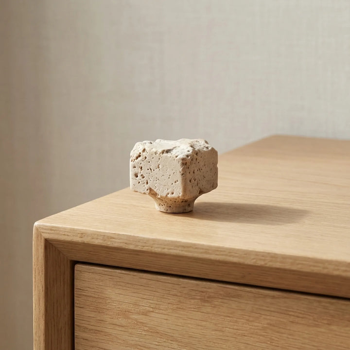 Travertine stone cabinet knob on natural oak bedside cabinet corner.