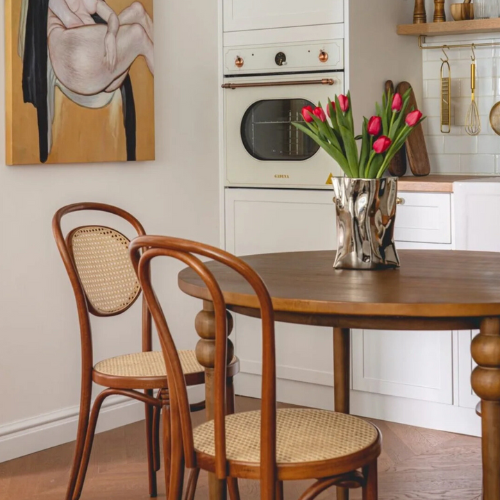 Tulip-filled silver vase on a Scandinavian-style kitchen table, blending rustic and modern design.