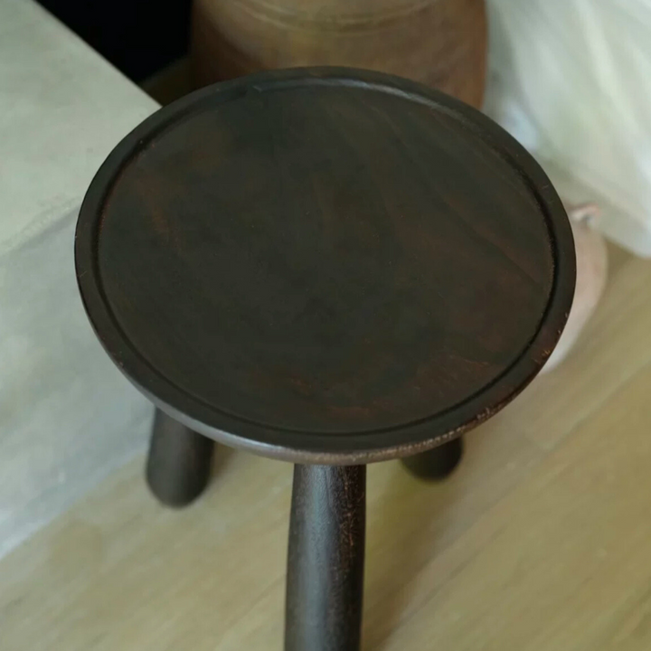 Close-up of a vintage wooden side table with textured finish and dark tones.