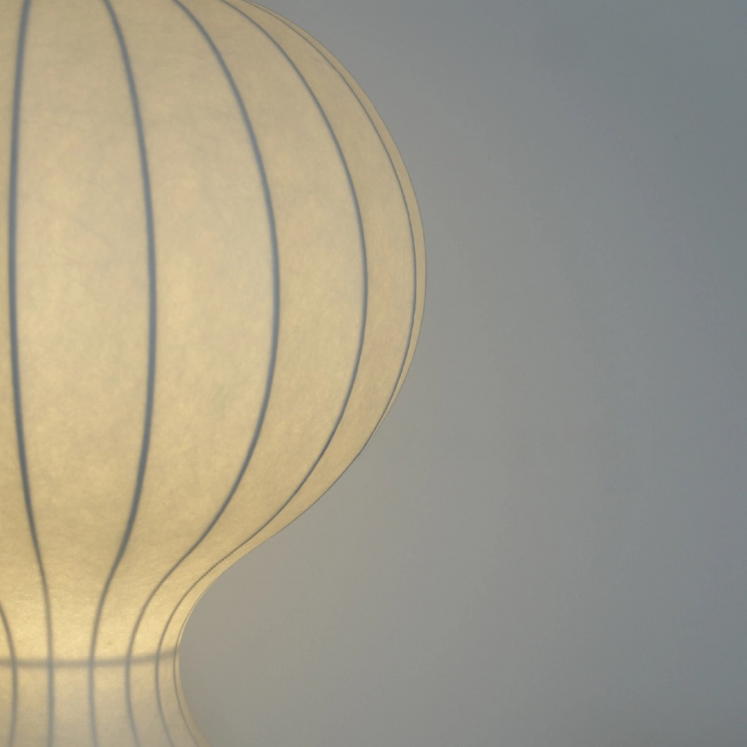 Sculptural table lamp close-up showing curved ribbed lines and soft matte finish.